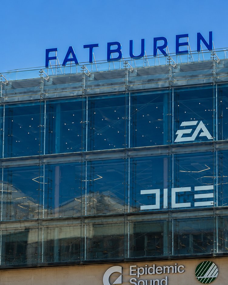 The EA DICE studio building on Södermalmsallén in Stockholm, its glass facade carrying the EA and DICE logos under a clear blue sky