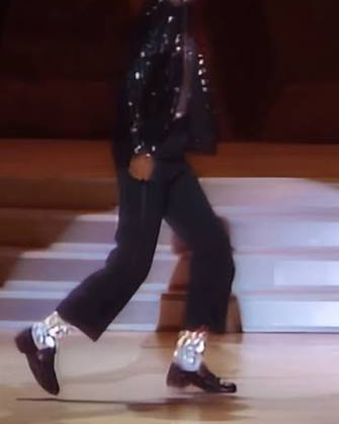 Michael Jackson mid-moonwalk during Billie Jean at Motown 25, gliding backward across the lit stage