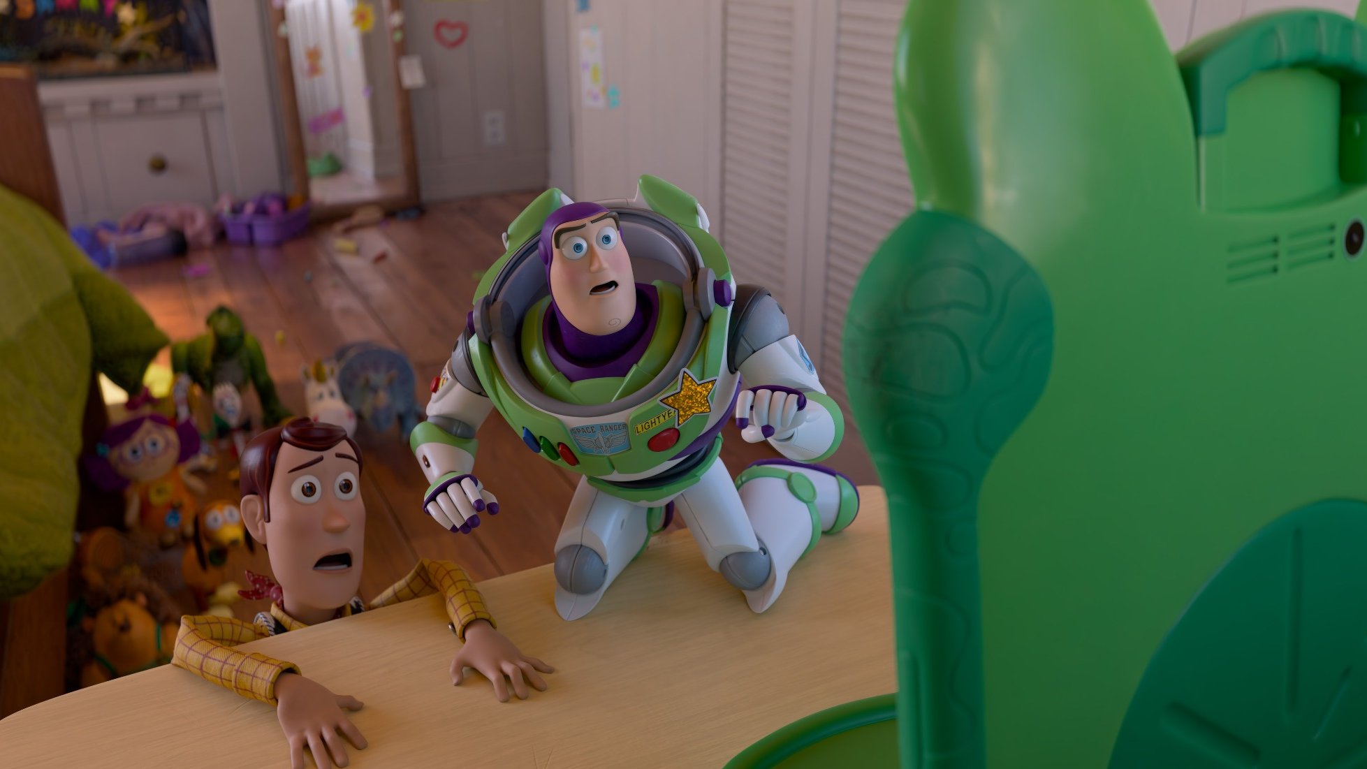 Woody and Buzz Lightyear staring up at Lilypad, the frog-shaped smart tablet that is the villain of Toy Story 5