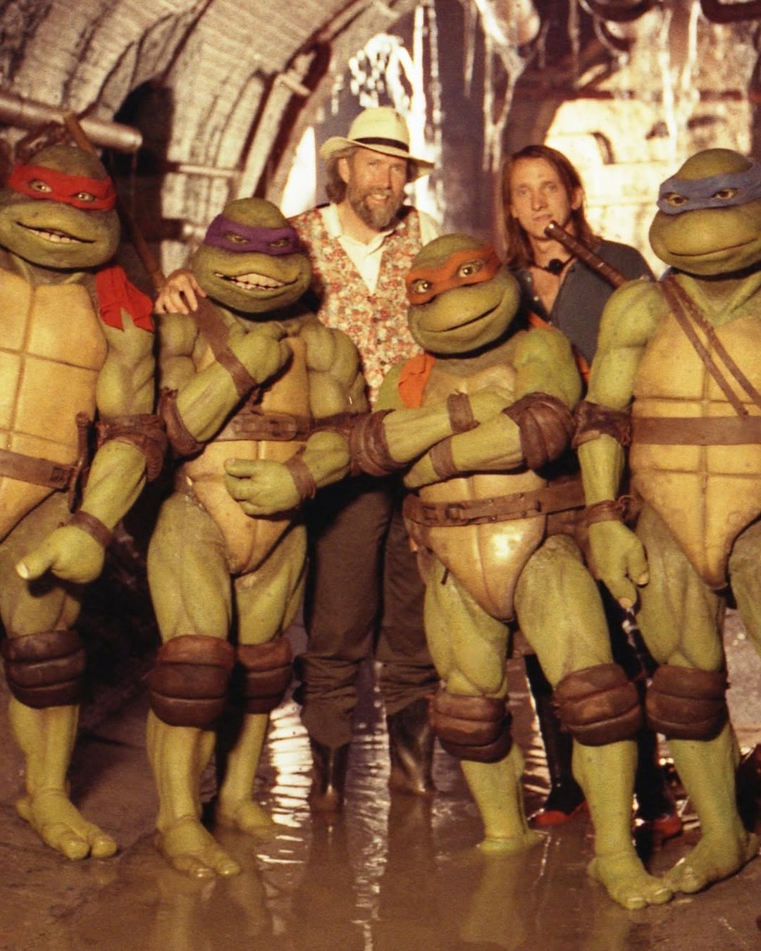 Jim Henson and director Steve Barron with the four Teenage Mutant Ninja Turtles in their Creature Shop suits, on the sewer set